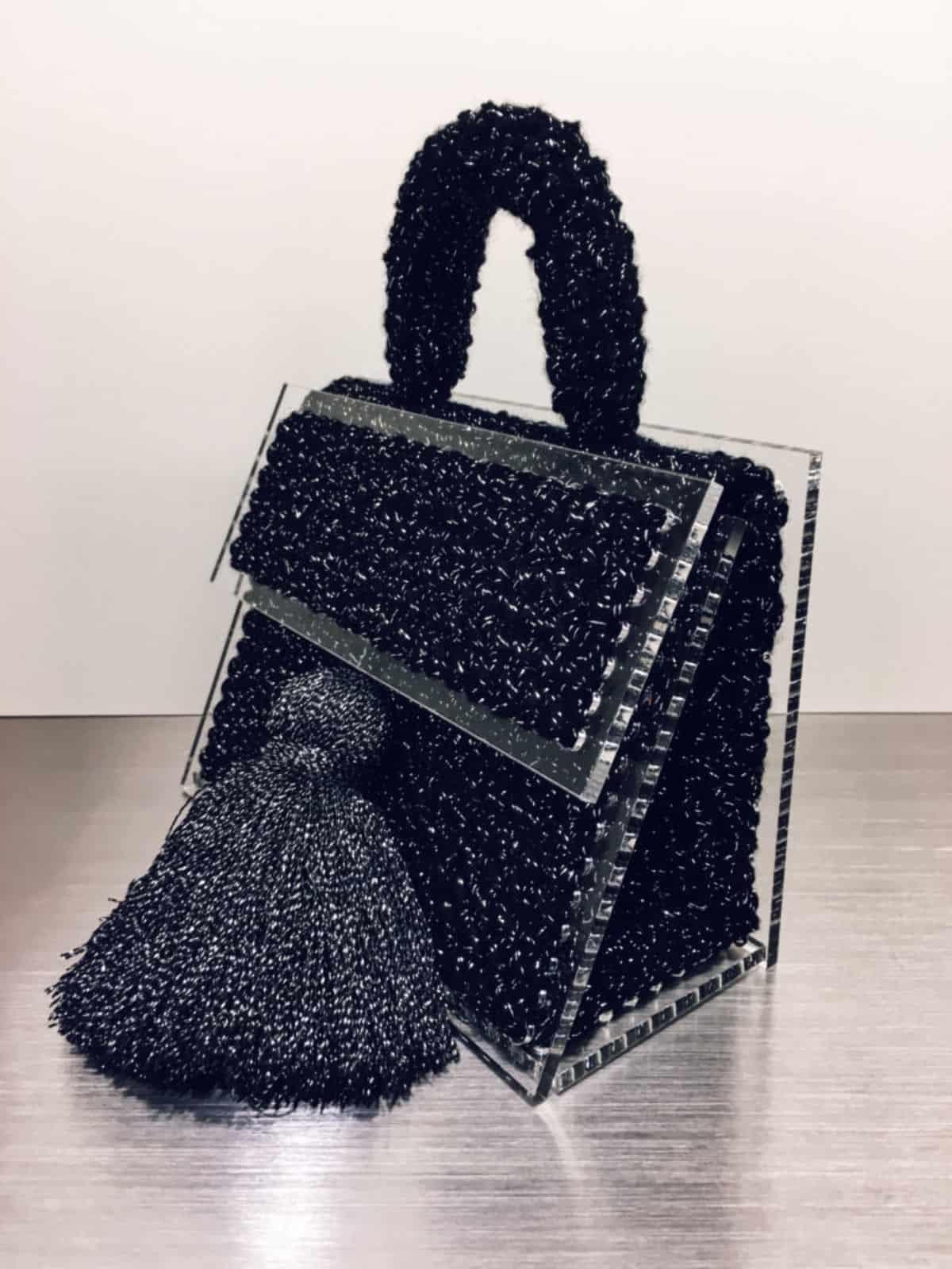 На фотографии женская маленькая черная сумка от Shapar, бренда вязаной одежды и аксессуаров ручной работы в интернет-магазине связанных спицами вещей.