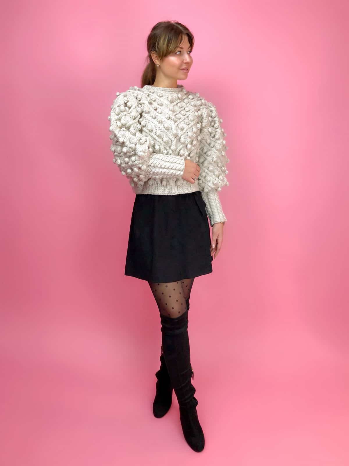 На фотографии женский свитер с помпонами от Shapar, бренда вязаной одежды ручной работы в интернет-магазине связанных спицами вещей.