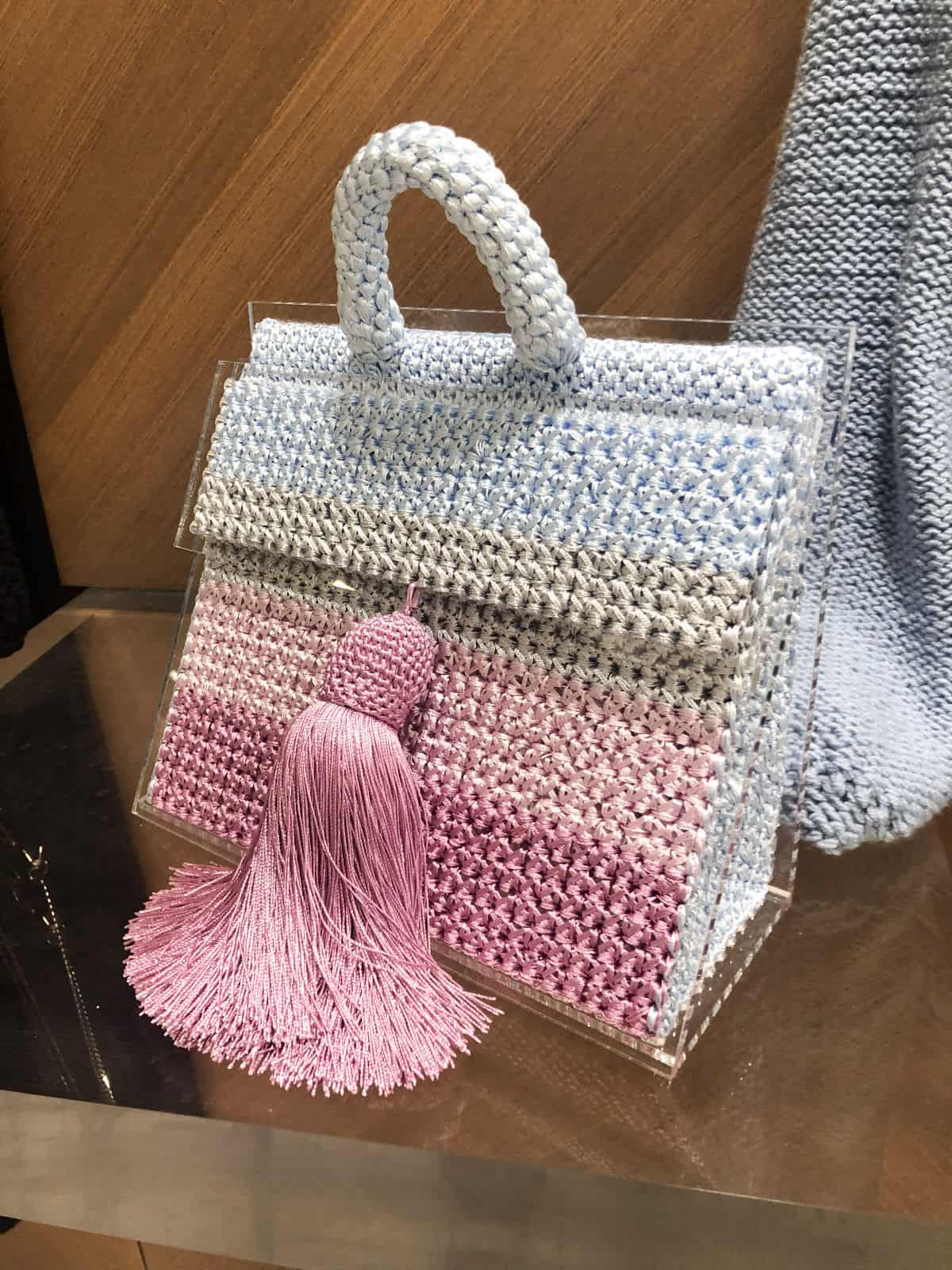 На фотографии женская вязаная сумка цветная от Shapar, бренда вещей и аксессуаров ручной работы в интернет-магазине связанной спицами одежды.