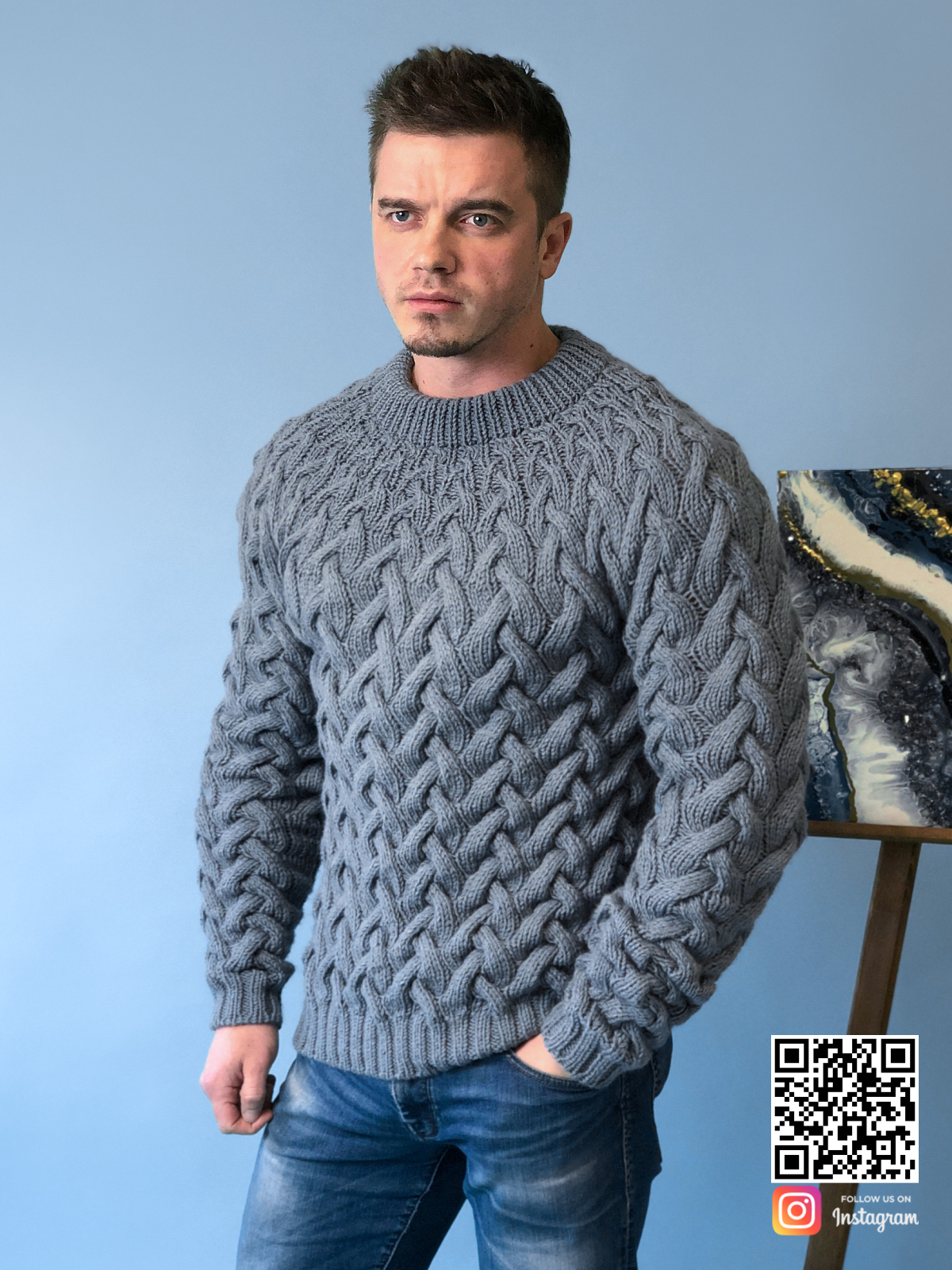 На фотографии мужской серый свитер косами от Shapar, бренда вязаной одежды ручной работы в интернет-магазине связанных спицами вещей.