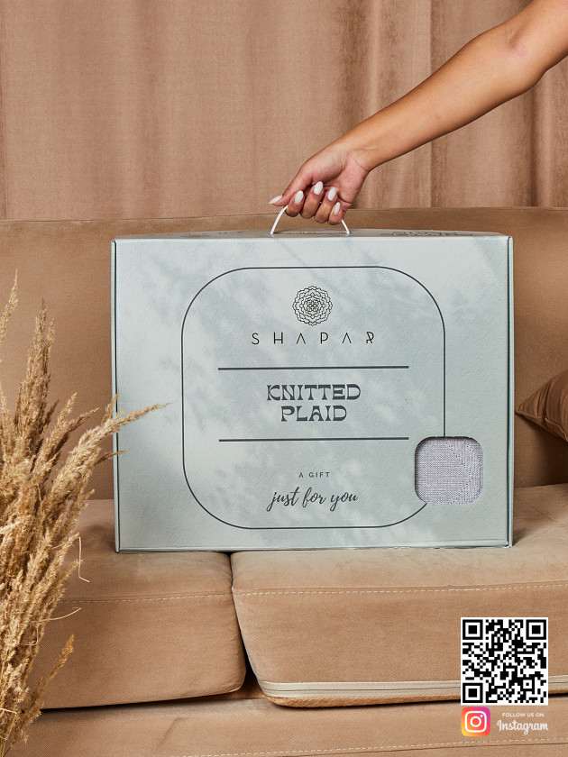 На второй фотографии вязаный плед серого цвета в упаковке в интернет-магазине Shapar, бренда трикотажа и связанной одежды ручной работы.