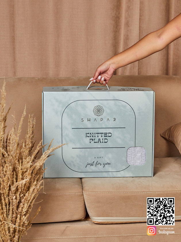 На второй фотографии вязаный плед косами в красивой упаковке в интернет-магазине Shapar, бренда трикотажа и связанной одежды ручной работы.